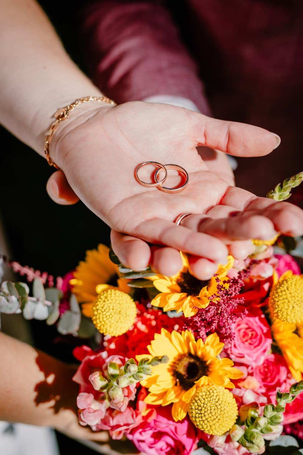 Eheringe auf den Handflächen der Braut über ihrem Brautstrauß